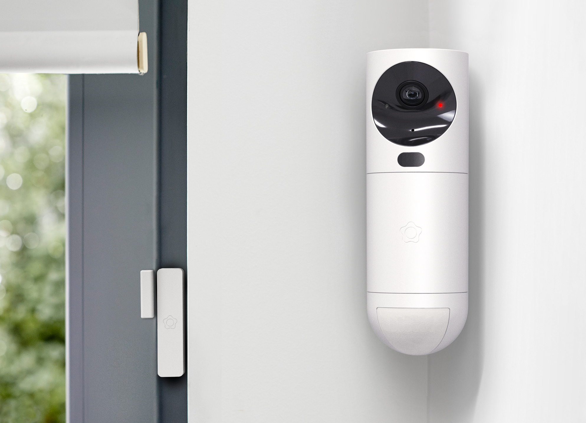Verisure security camera mounted on wall near window with sensor.