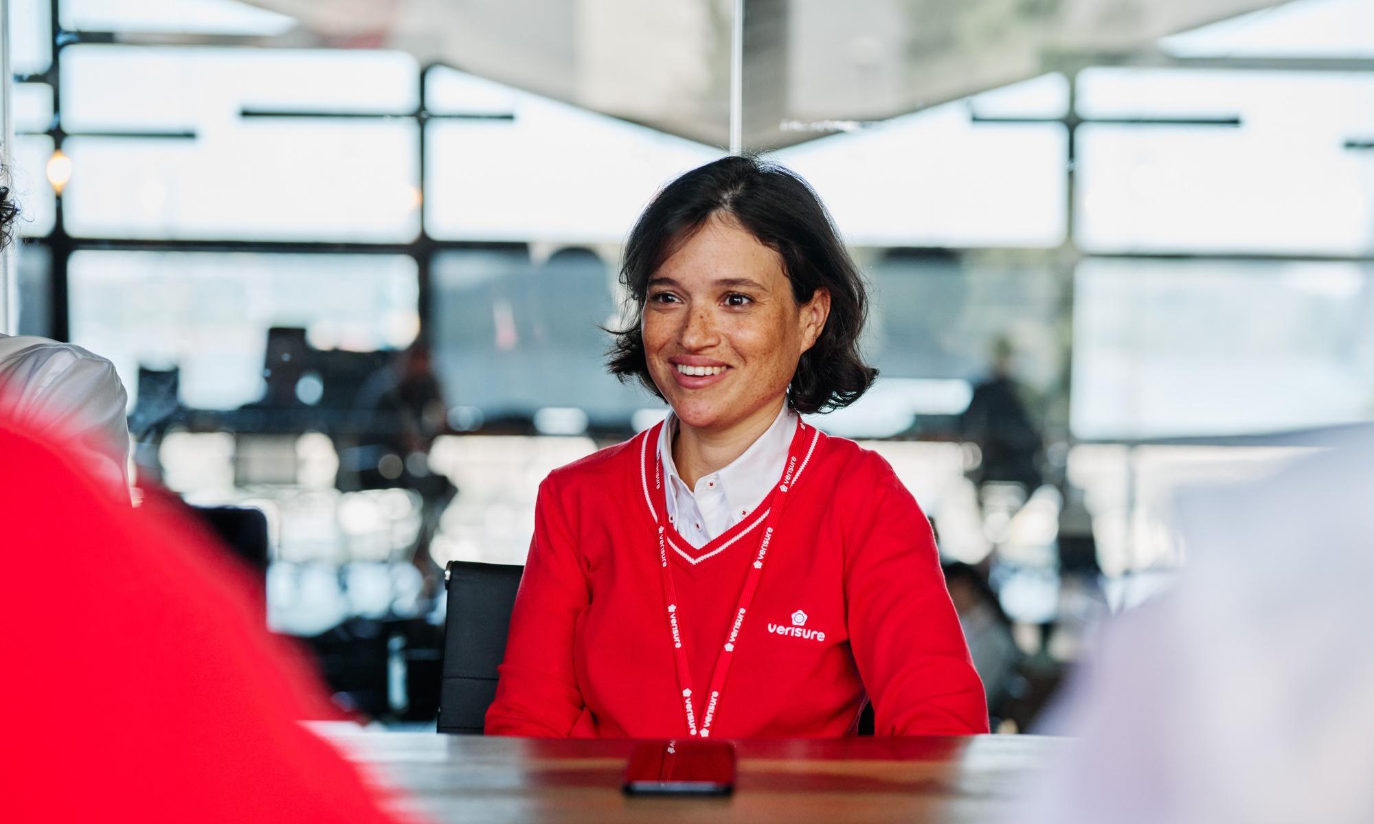 Female Verisure employee in red uniform speaking during meeting.