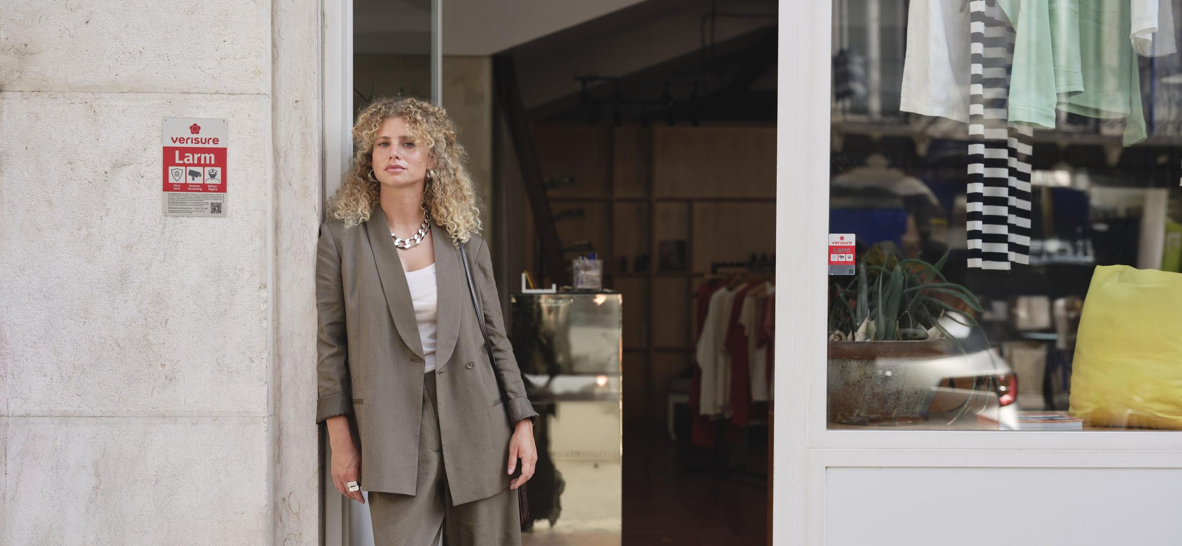 Woman standing outside store entrance with Verisure alarm sign on wall.