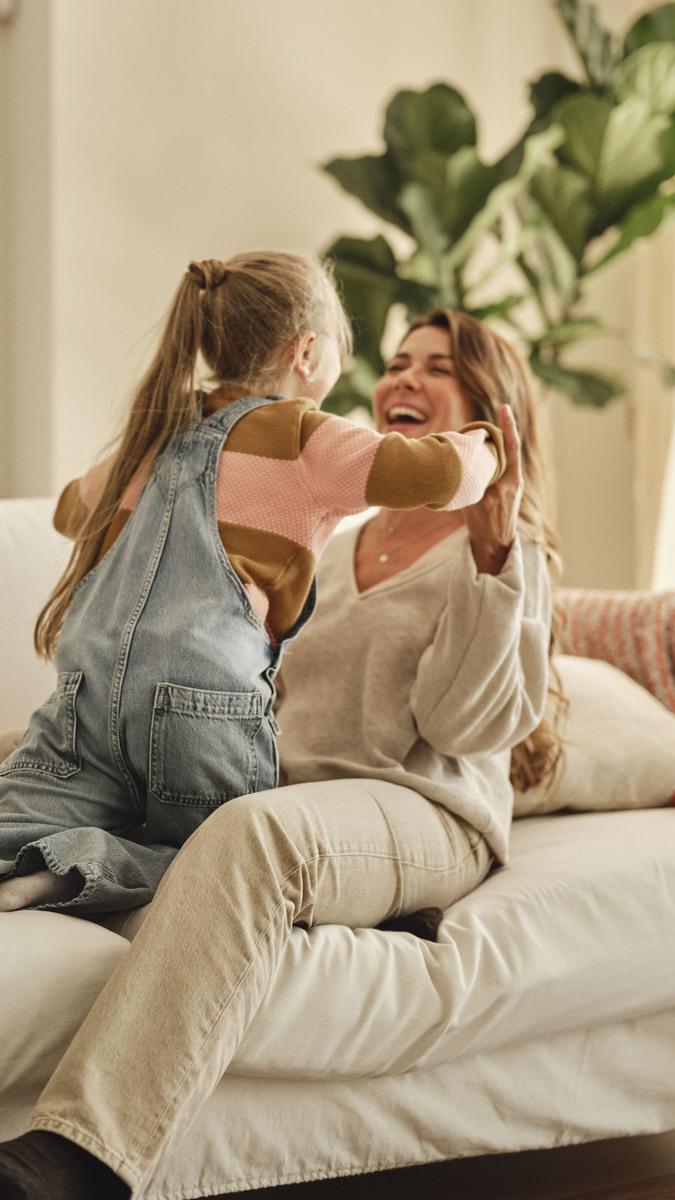 Mother and child sharing a joyful moment on a sofa at home, symbolising comfort, safety and family peace of mind.
